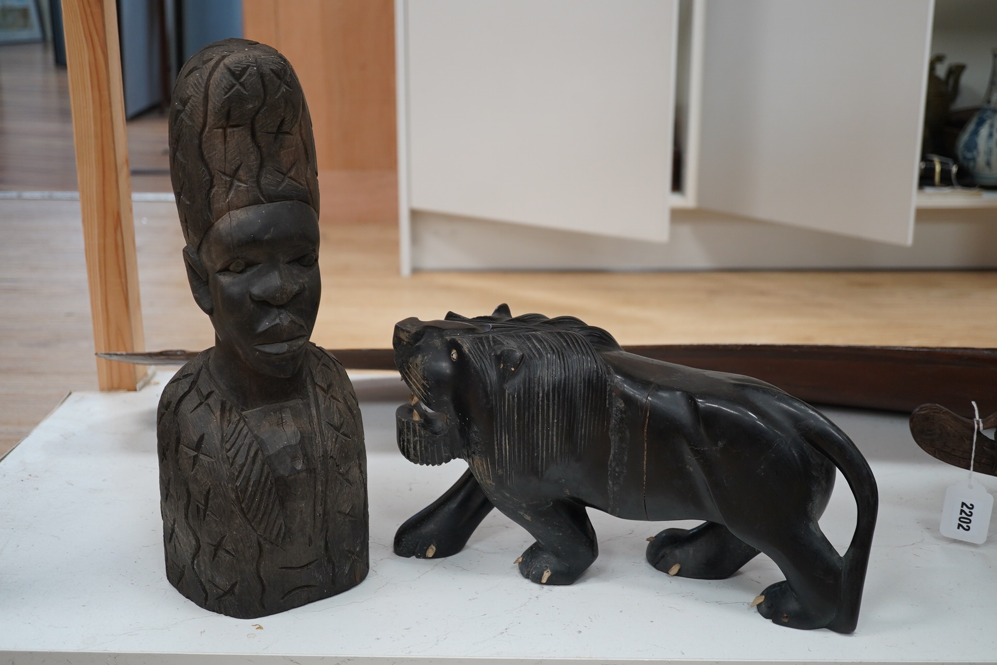 An African hardwood carving of a bust, 41cm high and an ebony Indian carving of a lion, 35cm long, (2). Condition - fair